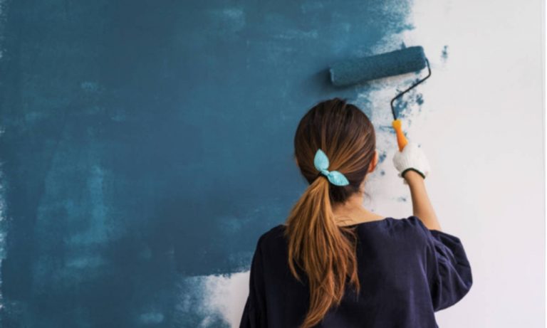 Pintar com spray ou rolo de tinta - mulher passando rolo de pintura na parede